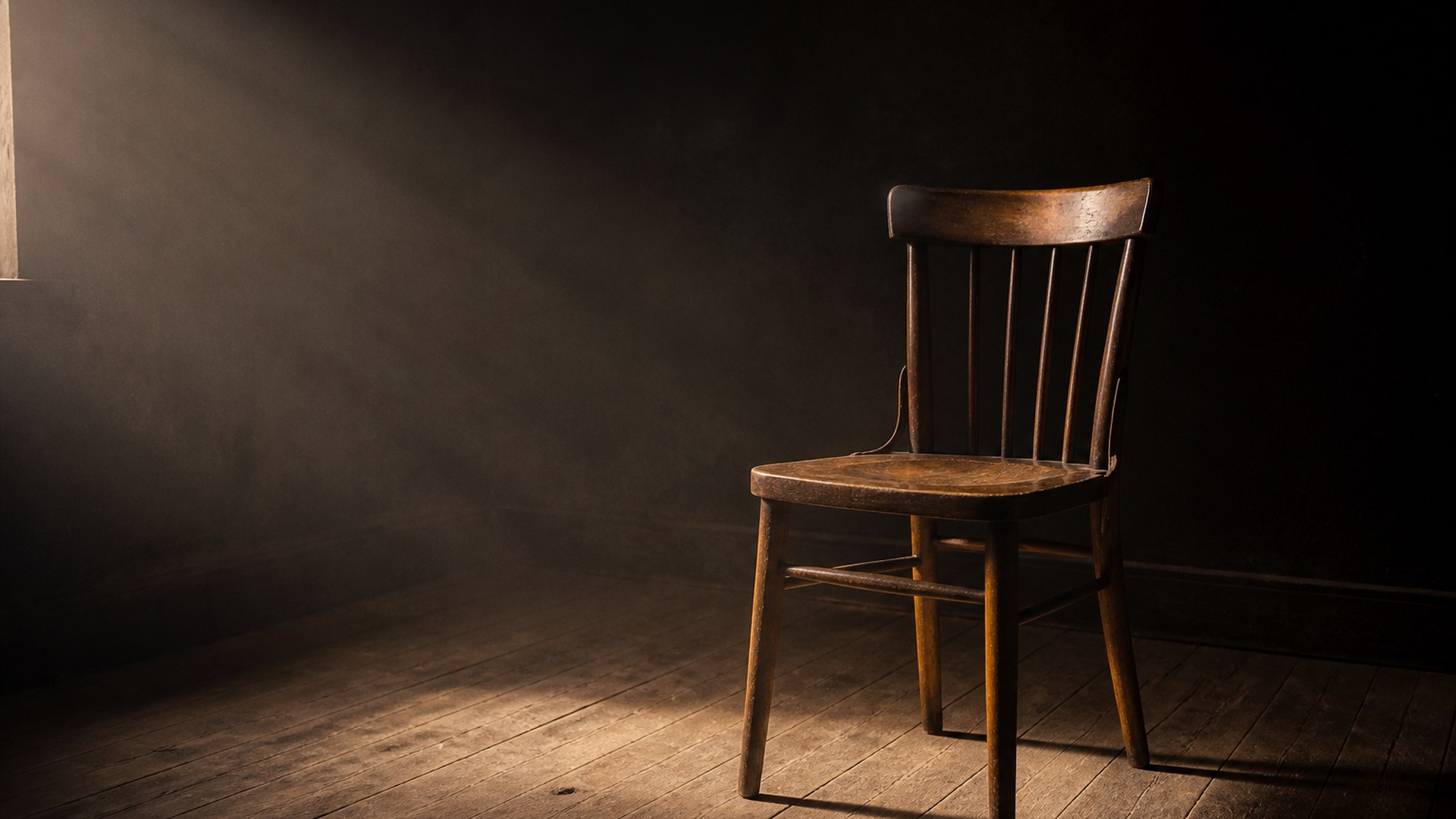 Twelve empty chairs in a tight circle around a small lamp in a dark room
