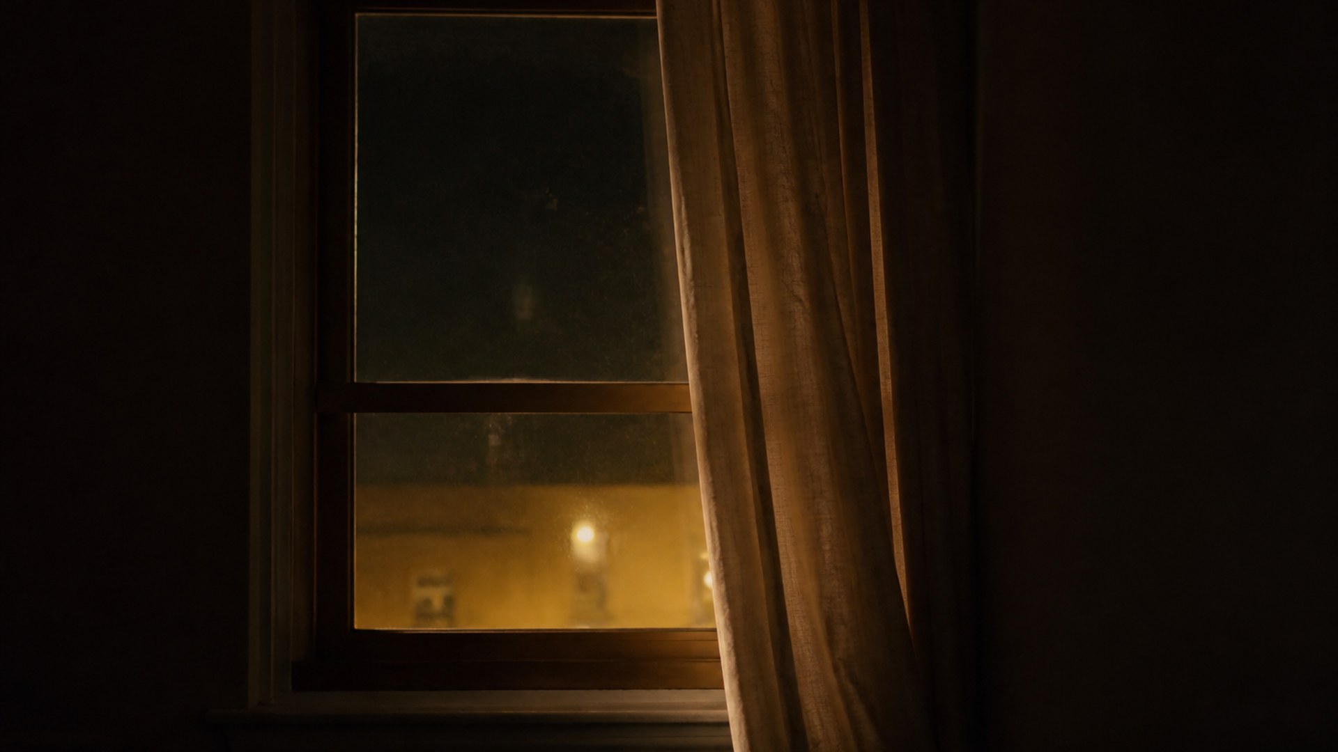 A small lit window in a vast dark landscape, dust in the night air